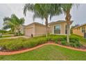 Tan single-story house with palm trees, well-manicured lawn, and a two-car garage at 1519 Emerald Dunes Dr, Sun City Center, FL 33573