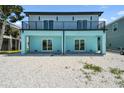 Home showcasing a backyard with white gravel, a full-length balcony, and sliding glass doors on the ground level at 3171 Sea Grape Dr, Hernando Beach, FL 34607