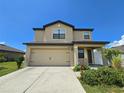 Two-story house featuring a tan exterior, two-car garage, and landscaping at 6949 Crested Orchid Dr, Brooksville, FL 34602