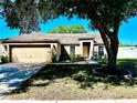 Single-story house with beige exterior, attached garage, and a well-manicured lawn at 5607 Brookdale Way, Tampa, FL 33625