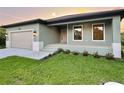 Newly built home showcasing a modern design, light green exterior, and a well-maintained lawn at 156 Haddock Dr, Rotonda West, FL 33947