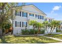 Charming two-story home featuring a balcony, manicured lawn, and decorative palm trees enhancing its curb appeal at 5002 W Homer Ave, Tampa, FL 33629