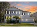 Two-story home with decorative palm trees and two-car garage, set against a stunning sunset sky at 5002 W Homer Ave, Tampa, FL 33629