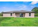 Rear view of a single story house with light brown exterior and a covered patio at 12461 Patsy Ave, Port Charlotte, FL 33981