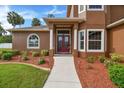 Home entrance with double red doors and landscape at 849 John Cressler Dr, Seffner, FL 33584
