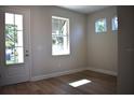 A bright room with wood floors, white trim, and ample natural light from a large window and glass paneled door at 7205 S De Soto St, Tampa, FL 33616