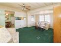 Cozy living room features green carpeting, a comfy sofa, and a view into the kitchen at 116 W Saint Johns Way, Apollo Beach, FL 33572
