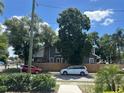 Gray house with a large tree in the front yard, parked cars and a wooden fence at 3008 N Nebraska Ave, Tampa, FL 33603