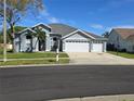 Charming single-story home featuring a three-car garage, manicured lawn, and beautiful landscaping at 28330 Openfield Loop, Wesley Chapel, FL 33543