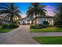 Luxury home with palm trees, brick driveway, and landscaped yard at dusk at 15908 Castle Park Ter, Lakewood Ranch, FL 34202