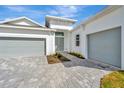 White two-car garage with gray doors and a brick driveway at 8328 Golden Beach Ct, Parrish, FL 34219