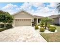 Tan house with a three-car garage, landscaping, and a paved driveway at 1013 Emerald Dunes Dr, Sun City Center, FL 33573