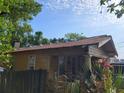 Yellow house with a rustic roof, front porch, and mature trees at 2607 E 26Th Ave, Tampa, FL 33605