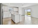 Open concept kitchen with white cabinets, an island, and a view to backyard at 10619 Hidden Banks Gln, Parrish, FL 34219