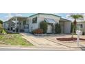 White single-wide manufactured home with green trim, carport, and landscaped yard at 107 E Saint Johns Way, Apollo Beach, FL 33572