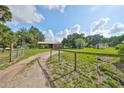 Fenced property with a long driveway, an open garage, and several outbuildings at 12922 672 Hwy, Riverview, FL 33579