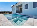 Gorgeous pool and spa with a safety fence is surrounded by a light blue house under a bright blue sky at 6542 Simone Shores Cir, Apollo Beach, FL 33572