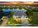 Luxury home aerial view at sunset, overlooking a lake at 7135 Graybrook Dr, Wesley Chapel, FL 33545