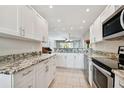 Modern kitchen with white cabinets, granite countertops, and stainless steel appliances at 8693 Bardmoor Blvd # 308B, Seminole, FL 33777