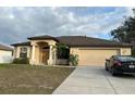 One-story home featuring a beige exterior, brown roof, and attached garage at 4458 Maverick St, North Port, FL 34288