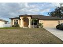 Single-story house with beige exterior, brown roof, and a two-car garage at 4458 Maverick St, North Port, FL 34288