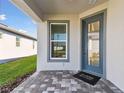 Inviting front entryway with a glass-paneled blue door and a brick-paved porch at 9413 Ballaster Pointe Loop, Parrish, FL 34219