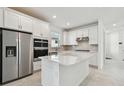 Modern white kitchen features stainless steel appliances, a kitchen island, and tile backsplash at 9421 Ballaster Pointe Loop, Parrish, FL 34219