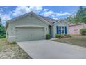 Green house exterior, two-car garage, and manicured lawn at 9538 Highland Ridge Dr, Hudson, FL 34667