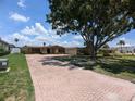 Lovely single-story home with a brick driveway, a spacious yard, and mature trees at 3931 E Eden Roc Cir, Tampa, FL 33634