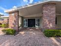 Home entrance featuring brick columns, a covered porch, and a well-maintained landscape at 3931 E Eden Roc Cir, Tampa, FL 33634