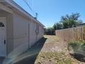 Side yard with neutral paint, a fenced perimeter, and exterior access door at 4305 E Deleuil Ave, Tampa, FL 33610