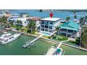 Aerial view of a waterfront home featuring a private dock and in-ground pool, surrounded by lush landscaping at 831 Bay Point Dr, Madeira Beach, FL 33708
