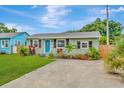 Inviting single-story home with a vibrant blue door, complemented by lush landscaping and driveway at 2866 15Th N Ave, St Petersburg, FL 33713