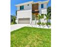 Well-manicured lawn leading to a modern two-story home with stylish landscaping and a two-car garage at 7615 S Swoope St, Tampa, FL 33616