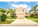 Two story house with beige exterior, two car garage, and palm trees at 409 Serenity Mill Loop, Ruskin, FL 33570