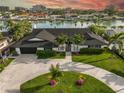 Well-maintained home featuring a lush, green lawn, a circular driveway and mature landscaping at 221 Howard Dr, Belleair Beach, FL 33786