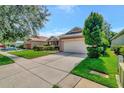 Single-story home on a tree-lined street with a two-car garage at 10906 Holly Cone Dr, Riverview, FL 33569