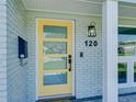 A bright yellow front door with four glass panels and a modern black handle stands out at 120 Chesapeake Ave, Tampa, FL 33606