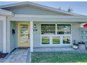 Close-up of the front door with a yellow frame, glass panels, house number, and white trim at 120 Chesapeake Ave, Tampa, FL 33606