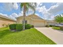 Tan house with a two-car garage and palm tree at 16903 Peaceful Valley Dr, Wimauma, FL 33598