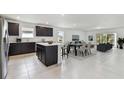 Bright, open kitchen featuring dark cabinetry, a center island, and stainless steel appliances at 12744 Wanderlust Pl, Parrish, FL 34219
