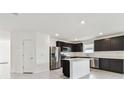 Modern kitchen featuring dark cabinets, stainless steel appliances, and an island at 12744 Wanderlust Pl, Parrish, FL 34219