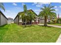Landscaped yard with lush grass, palm trees, and a covered porch at 10012 Sage Creek Dr, Ruskin, FL 33573