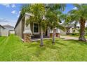Landscaped yard with lush grass, palm trees, and a covered porch at 10012 Sage Creek Dr, Ruskin, FL 33573