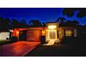 Night view of a well-lit home featuring a two car garage, tiled pathway, and a manicured front yard at 11416 Billingham Blvd, Spring Hill, FL 34609