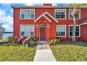 Two-story townhome with a red exterior, small front yard, and seating area at 9036 Lake Chase Island Way # 9036, Tampa, FL 33626