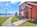 Red townhome with a lake view and a small, landscaped front yard at 9036 Lake Chase Island Way # 9036, Tampa, FL 33626