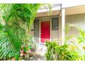 Red front door entrance with lush tropical landscaping at 758 Pine Run Dr # 758, Osprey, FL 34229