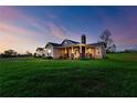 Inviting exterior view of a home with a cozy porch, stone accents, and manicured green lawn at dusk at 36431 Florrie Mae Ln, Dade City, FL 33523