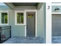 Charming townhome entrance with a gray door, paver patio, and modern exterior light at 5530 N 9Th St # 3, Tampa, FL 33604